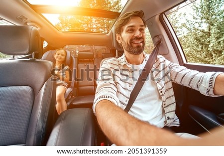 Child cute girl in a car seat protected by seat belts with her dad going in the car for the weekend. Leisure, travel, tourism. Stock foto © 