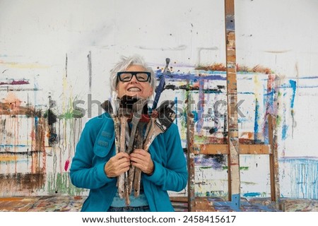 Similar – Image, Stock Photo Senior artist standing in home workshop and choosing paints