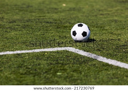 Black and white soccer ball on green soccer pitch.