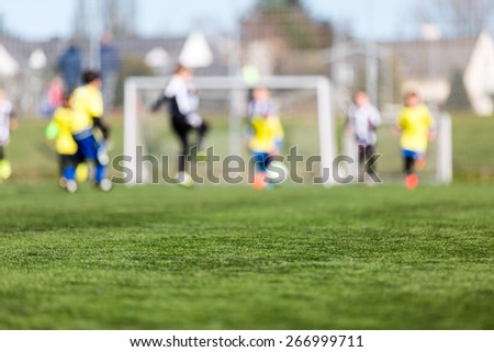 Blur of young kids playing a youth soccer match outdoors on an green soccer pitch.