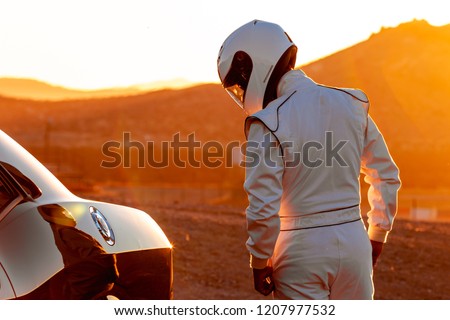 A Helmet Wearing Race Car Driver In The Early Morning Sun Looking At His Car Before Starting Stock foto © 