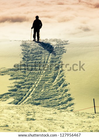 Silhouette of a skier who stands at the top of the hill.