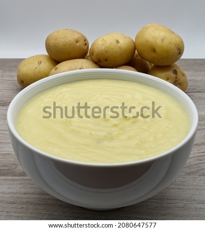 Mashed potatoes in a bowl, raw potatoes on background. Foto d'archivio © 