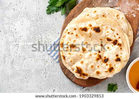 Homemade Roti Chapati Flatbread  on gray concrete background top view. Freshly baked indian flatbread. Copy space for text.