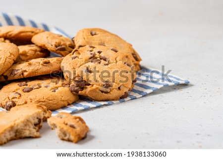 Heap of chocolate chip cookies on a gray table close-up. Sweet breakfast. Stack of traditional chip cookies with chocolate chunks.