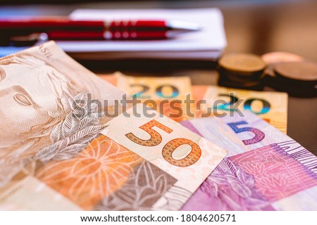 Real, money from Brazil. Dinheiro, Brasil, Reais, Real brasileiro. A group of Real banknotes and coins on a table.