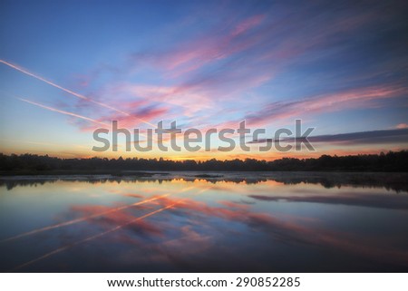 Beautiful sunrise with bright clouds reflected in water
