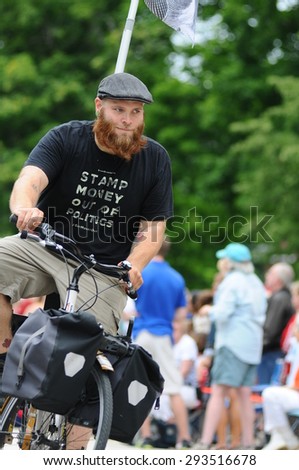 A man campaigning for campaign finance reform rides a bicycle in the July 4 parade in Amherst, New Hampshire, on July 4, 2015.