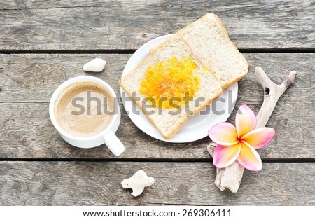 Cup of coffee and bread slice with orange jam.