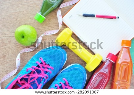 Fitness concept ,fresh fruits, juice bottle and record book on tile floor.