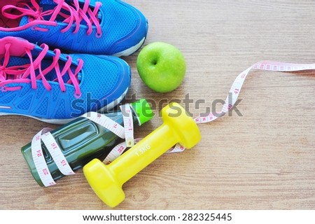 Set for sports activities and detox juice on tiled floor.
