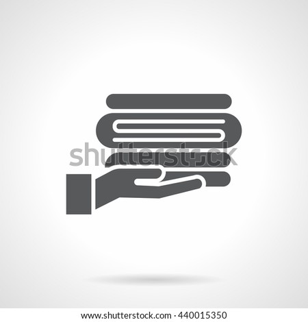 Hand giving folded linen. Hotel service, towel delivery for bath and shower. Linens for bed, laundry and drying sign. Symbolic black glyph style vector icon. 