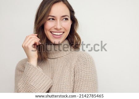 Portrait of young happy beautiful woman smiling and standing isolated on white background in a warm sweater. Young female girl with a perfect smile looking right. Foto stock © 