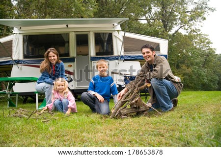 Camping: Cute Family Poses By Campfire Near Pop-Up Trailer