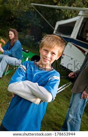 Camping: Boy Holding Tongs By Trailer
