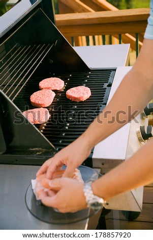 Family: Man Putting Meat On Grill To Cook