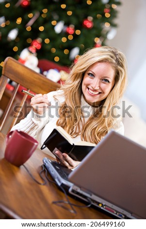 Christmas: Smiling Woman Making Christmas List While Online Shopping
