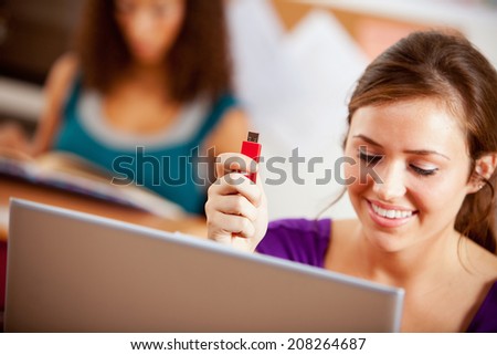 Students: Smiling Girl Holds Up USB Flash Drive By Laptop