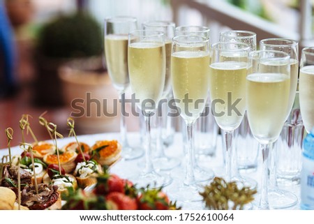 Elegant glasses with chilled champagne stand in row next to canapes and snacks on picturesque background. Party and holiday away. Picnic. Photo stock © 