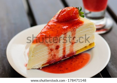 Crepe cake full with strawberry sauce, focus on a fresh strawberry