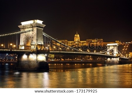 The Szechenyi Chain Bridge over Danube river in Budapest, Hungary - World famous Chain Bridge from Pestan side with royal palace on Buda hill by night
