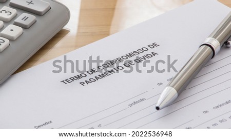 A DEBT PAYMENT COMMITMENT TERM AGREEMENT FORM in Portuguese language on the desk. Calculator and pen on the table Stok fotoğraf © 