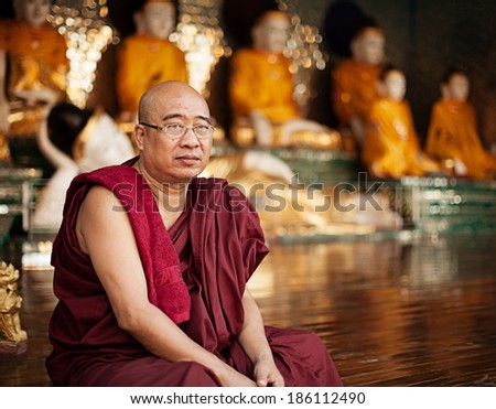 YANGON, MYANMAR - 03 JAN 2014: Tired monk sits near a Buddhist complex.