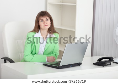 The beautiful young girl - the manager sits at a table at office