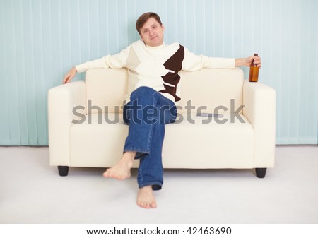 The young guy has a rest on a sofa with beer and the TV