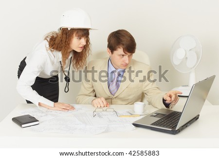 Two young engineers work over the project on the laptop