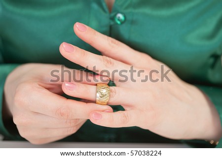 A woman tries on a large gold ring on his finger