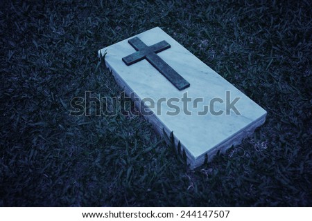 Black and white image of a cross on a marble slab, marking a grave at this cemetery in Singapore