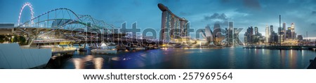 SINGAPORE - 01 JAN 2014: Skyline from the embankment. High-rise buildings, ferris wheel, bridge, ArtScience Museum and Marina Bay sands Hotel