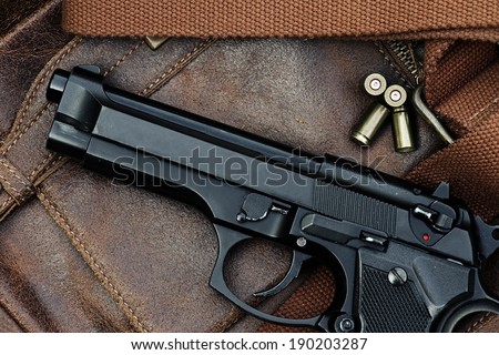 Semi-automatic handgun lying over a Leather handbag, 9mm pistol, Close-up