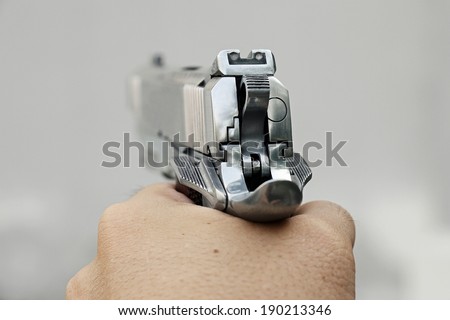 Human hand holding gun, hand aiming a handgun, .45 pistol.