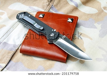 Pocket knife, Black tactical knife on military background.