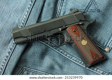 Semi-automatic handgun on blue jeans background, .45 pistol.