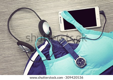 Gym outfit - workout clothing, running shoes, headphones and smartphone to listen to music while working out at the fitness center. Matching clothes, sports bra. (Vintage Style Color)