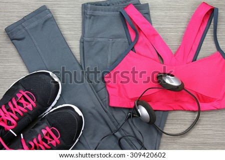 Gym outfit - workout clothing, running shoes, headphones and smartphone to listen to music while working out at the fitness center. Matching clothes, sports bra.