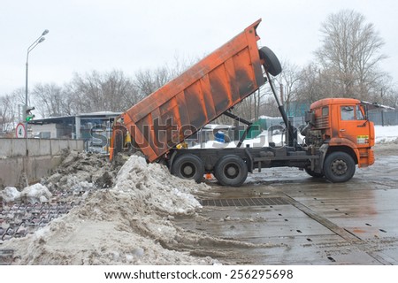 MOSCOW, RUSSIA - February 13, 2015: The discharge of snow from the body of the orange truck in negotable on snow-melting point, Moscow