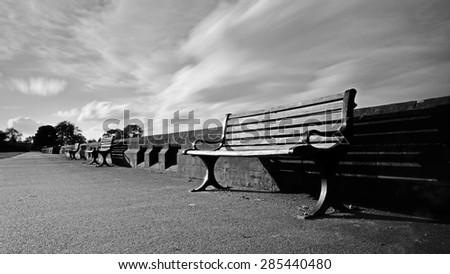 black and white image of a row of empty park benches in a row in Stanley Park Liverpool