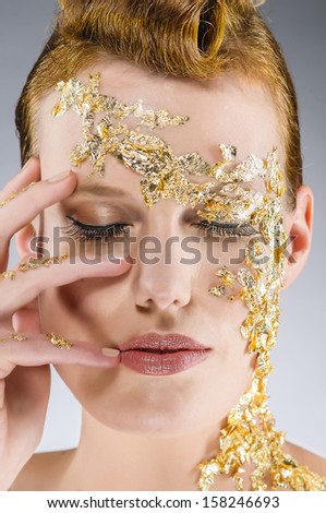 Portrait of a young woman with an elegant gold leaf make-up and closed eyes.
