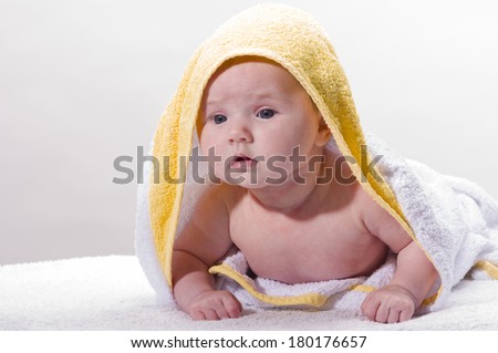 Sweet newborn baby wrapped in a towel and smiling, isolated against a white background.