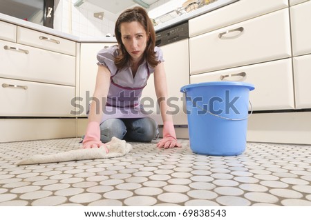 Adult housewife cleans the floor with mop and bucket in her kitchen