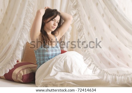 Young girl with long brunette hair rolls around in your pajamas on Sunday morning in the canopy bed.