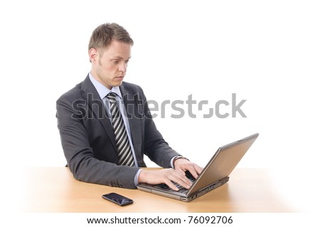 Young businessman in suit and tie sits at his desk, he wonders, looking in his notebook PC. Isolated against a white background