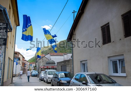 Mostar, Bosnia and Herzegovina- 9 July, 2014: daily street view of downtown Mostar, people on the street and national flag is hang on the light line. In sunny day.