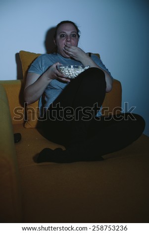 Overweight woman watching horror movie on TV