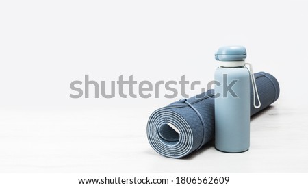 Rolled blue yoga mat and blue water bottle on grey wooden surface. Gender neutral fitness yoga and exercise concept with copy space. Active lifestyle. Workout at home or gym banner ストックフォト © 