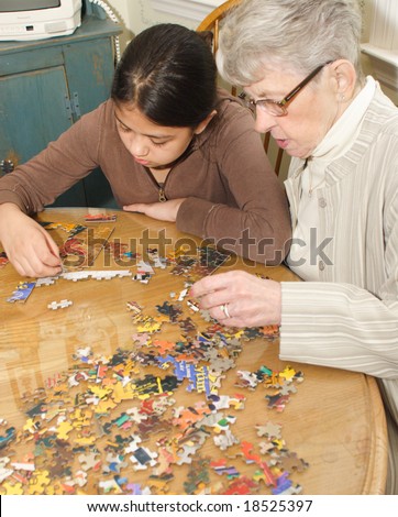 Grand daughter and grand mother working on jigsaw puzzle on kitchen table